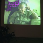 video image still of older guyanaes woman sitting on a couch